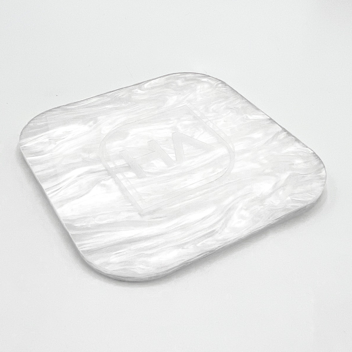 Pearl-finish white acrylic sheet sample, rounded square piece with glossy swirls