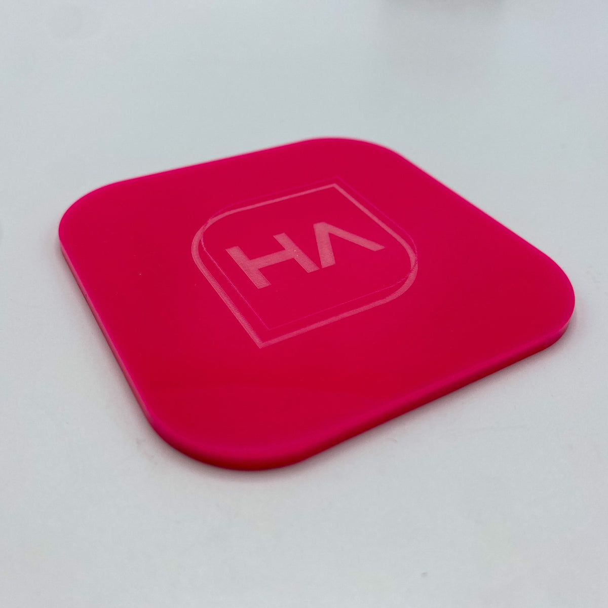 Hot pink glossy acrylic panel with embossed HA logo, rounded square corners