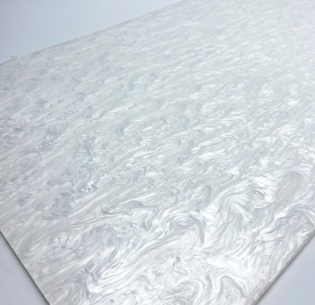 Pearl-finish white acrylic sheet close-up, swirled pearly marbling texture